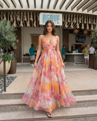 Woman in a floral dress standing on steps with 'Aguave' branding in the background