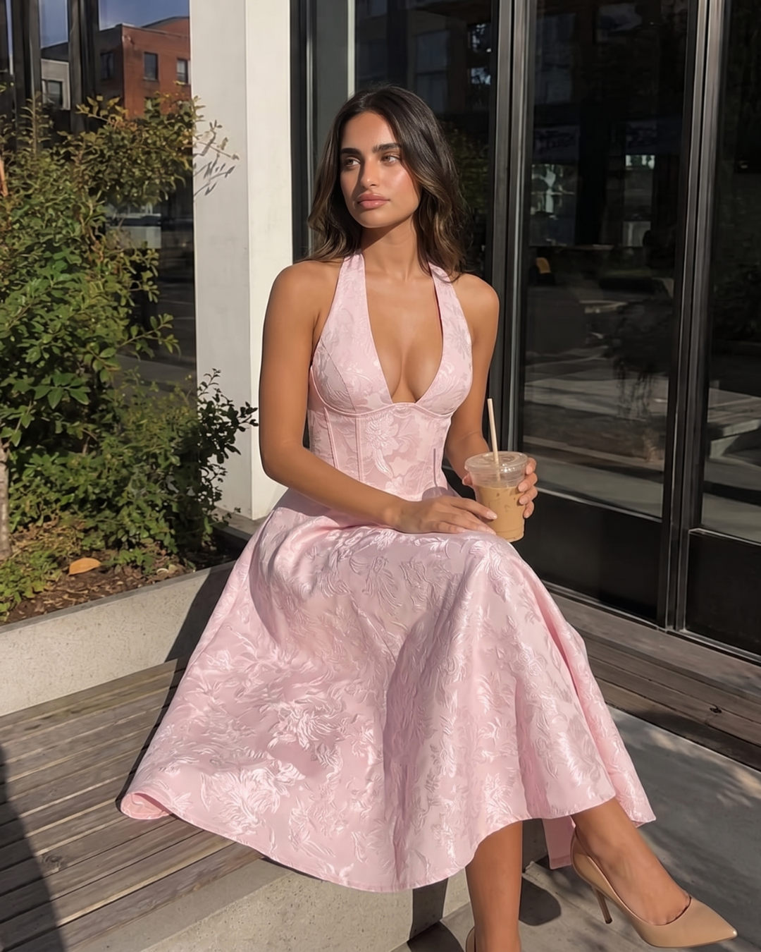 Woman in a pink dress holding a drink outside a building