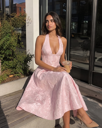Woman in a pink dress holding a drink outside a building